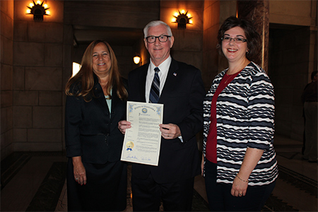 Treasurer Stenberg holds the proclamation proclaiming September as College Savings Month with Deborah Goodkin of First National Bank, left, and Rachel Biar.